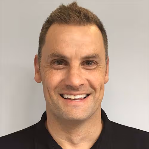 Smiling man with short brown hair wearing a black polo shirt